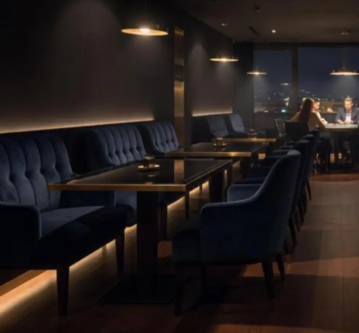 Prémium, sötét tónusú lounge tér elegáns pókerasztalokkal